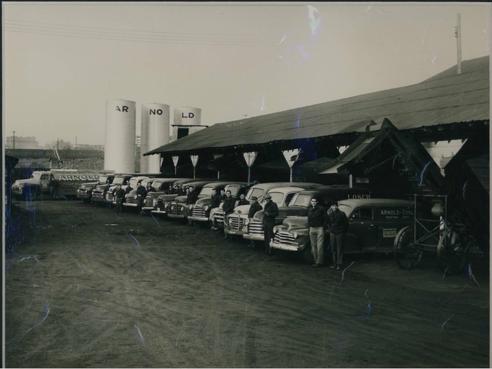 Arnold Coal and Supply 1940, our parent company, pictured with delivery trucks, drivers, and storage tanks.